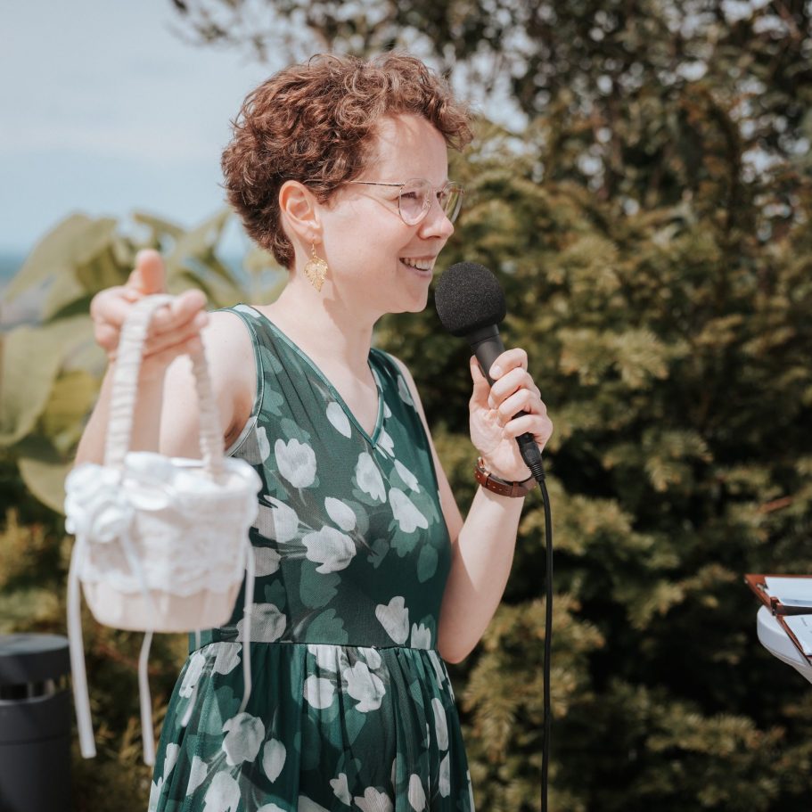 Traurednerin Anja Graf spricht auf einer Hochzeit in ein Mikrofon, das sie in der Hand hält.